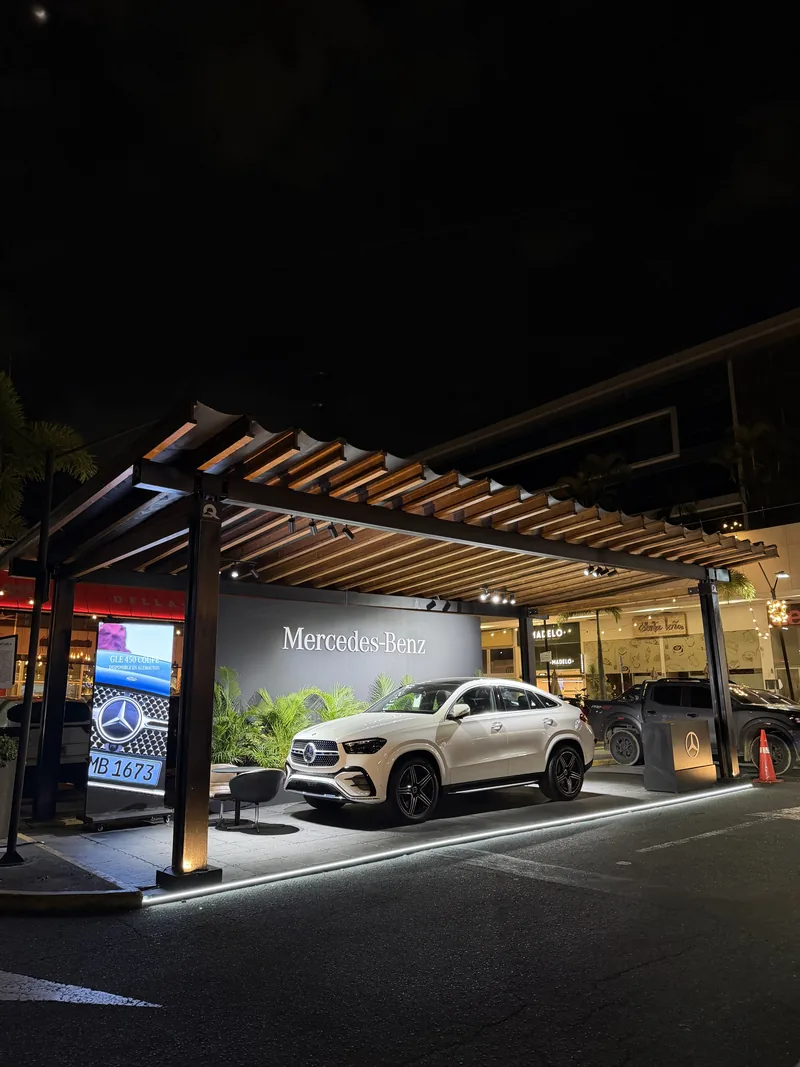 Carro de Mercedes-Benz en exhibición bajo pérgola de madera, de noche