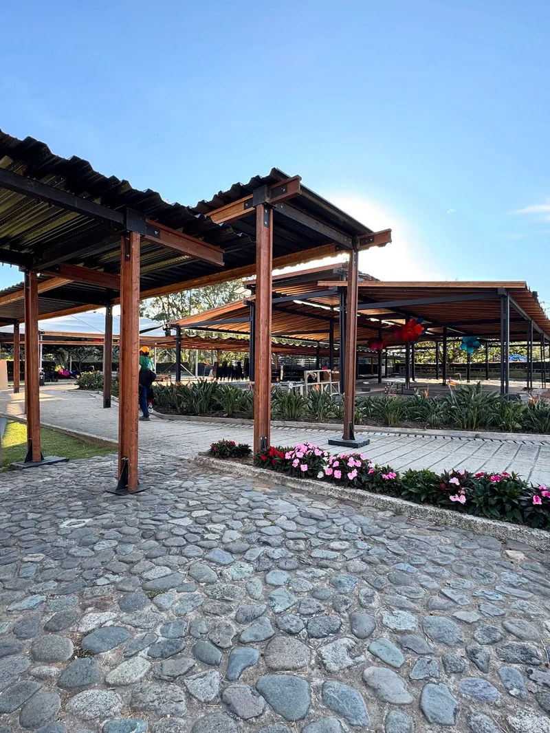 Pérgolas de madera sobre un sendero empedrado con jardines