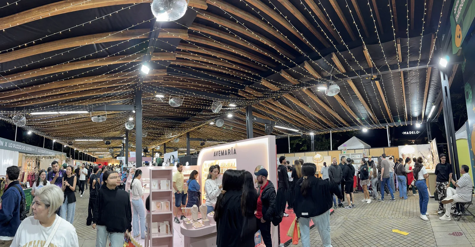 Feria de stands bajo una gran cubierta de madera con guirnaldas en EAFIT