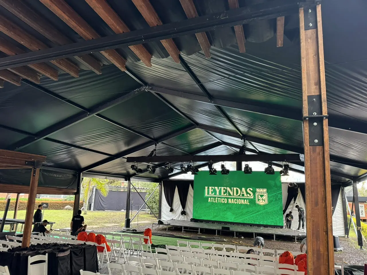 Cubierta de madera y acero frente a un escenario con pantalla