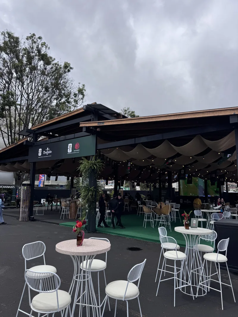 Granero de madera con mesas altas blancas en el FIFA Fan Fest de Bogotá