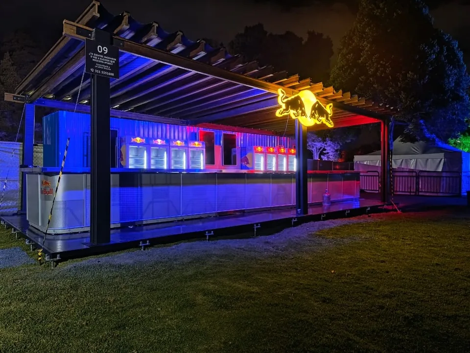 Barra de Red Bull de noche bajo pérgola con luz azul y roja