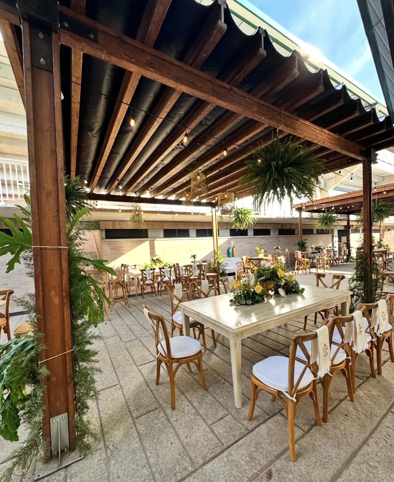 Mesa de boda con flores blancas bajo pérgola de madera
